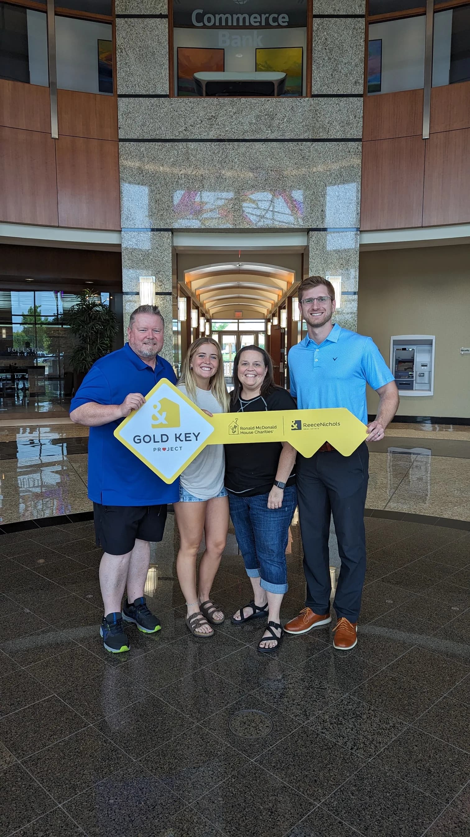 A family of four holding the Gold Key sign