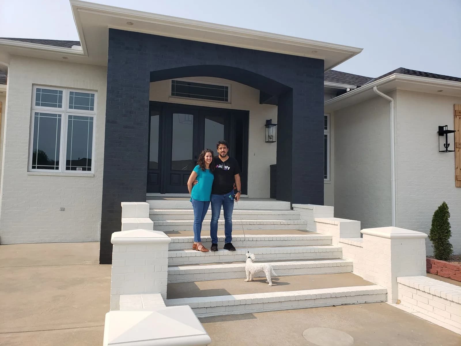 A couple and their dog on the steps of their new home