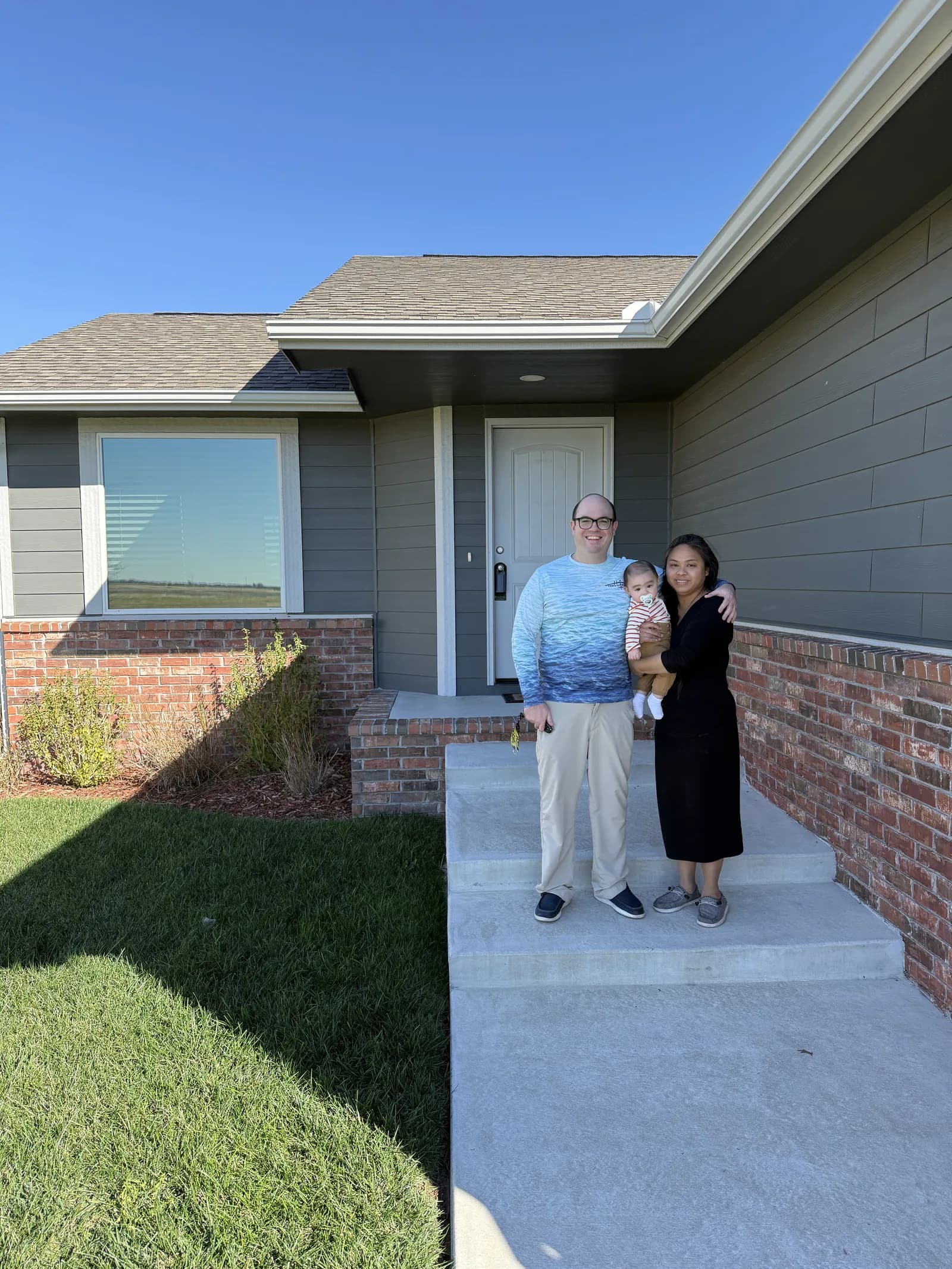A family with their baby on the porch of their new home