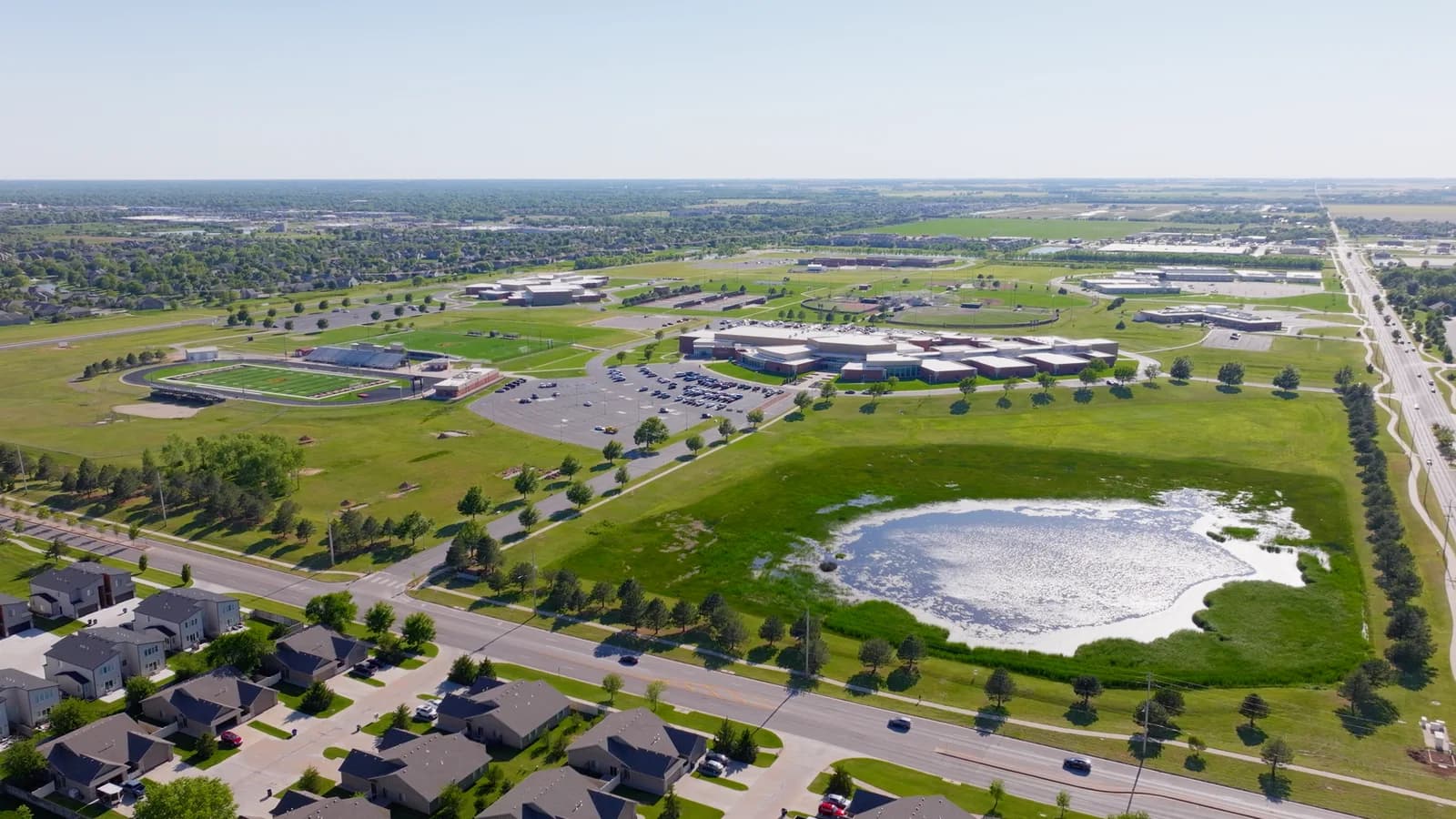 Aerial view of new rooftops and a pond in a growing Maize neighborhood